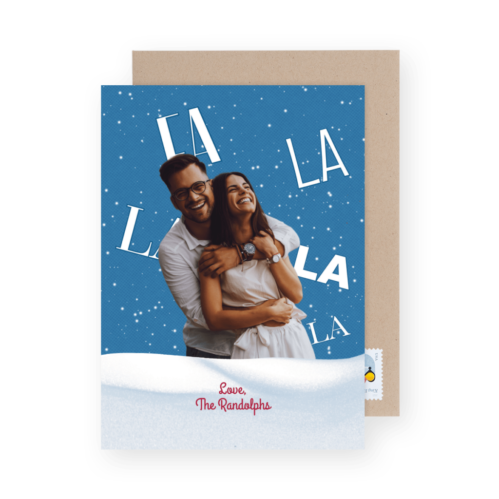 Holiday card with a couple hugging and smiling against a blue snowy background. The words "LA LA LA" are in the background and "Love, The Randolphs" is printed below.