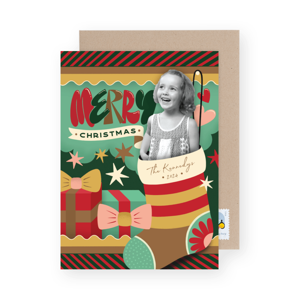 Colorful Christmas card with gifts and a stocking, featuring a black-and-white photo of a smiling child. Text reads "Merry Christmas."