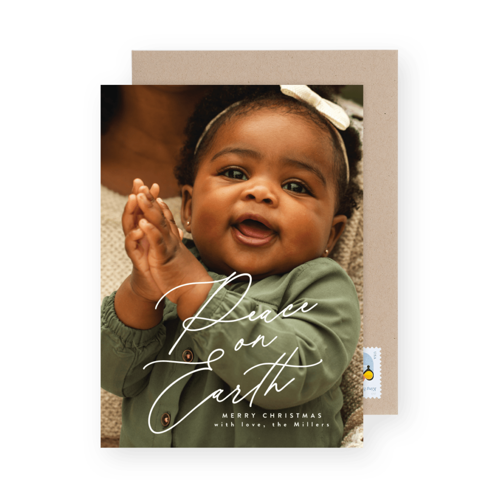 A baby in a green outfit claps with "Peace on Earth, Merry Christmas" written on the image.