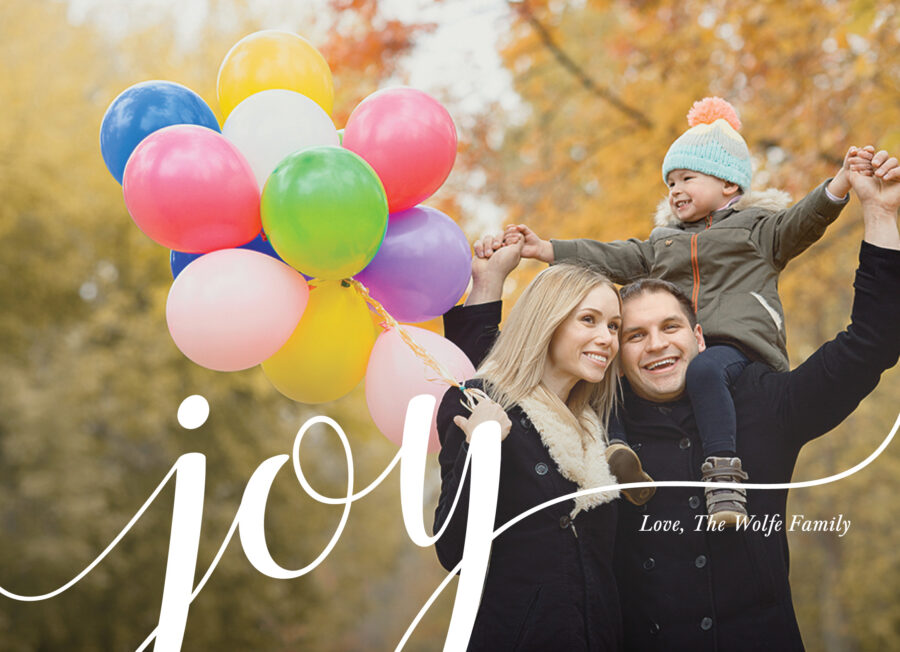 A family of three enjoys an autumn day outdoors. The mother holds colorful balloons, and the father carries their child on his shoulders. The word "joy" is written across the image.