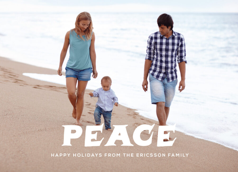 A couple and a toddler walk on a beach near the ocean. The text reads "Peace - Happy Holidays from the Ericsson family.