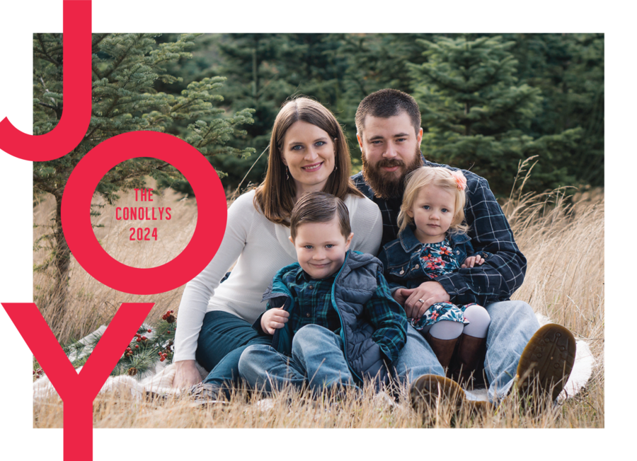 A family of four sits on the grass outdoors, surrounded by trees. The image has the word "JOY" in large red letters and "The Conollys 2024.