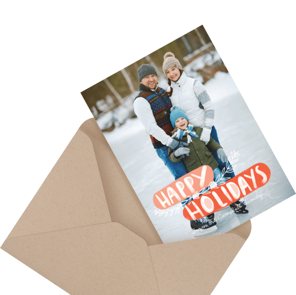 A family of three stands on an ice rink in winter clothing on a holiday card with "Happy Holidays" text. The card is partially inside an open brown envelope.