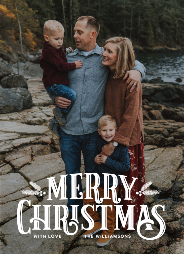 Family of four posing on rocky terrain by a river, with "Merry Christmas with love, The Williamsons" written in white vintage font at the bottom.