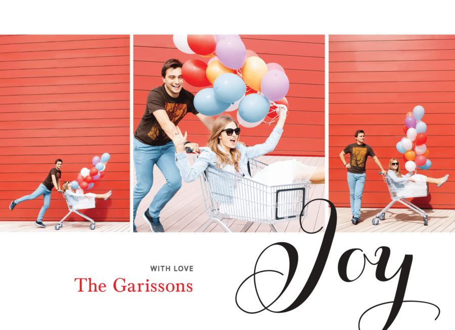 A couple playfully poses with a shopping cart and colorful balloons in front of a red wall.