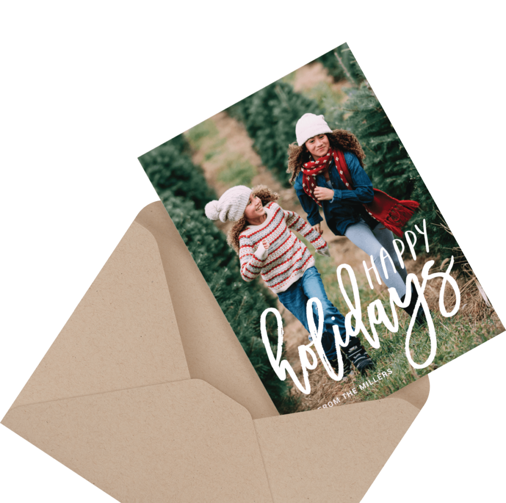 A holiday card showing two people in winter clothing running through a tree farm, with the text "Happy Holidays" on the front.