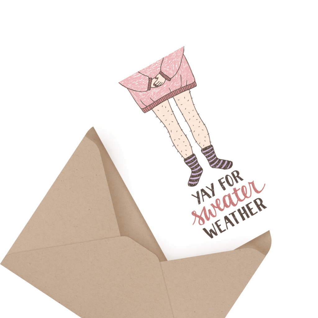 A greeting card partially inside an envelope shows a person in a pink sweater and socks with text "Yay for sweater weather.