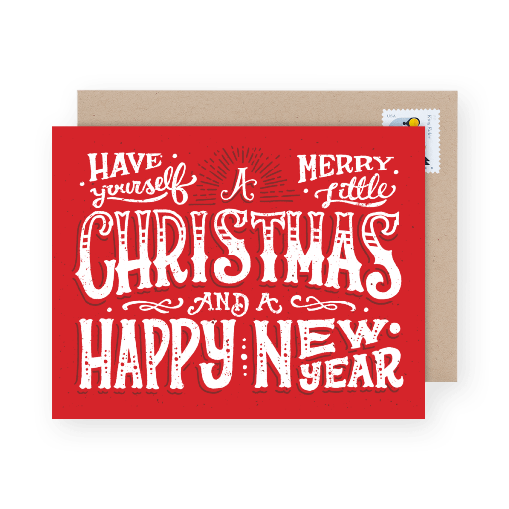 Red greeting card with the text "Have Yourself a Merry Little Christmas and a Happy New Year" in white decorative font, placed in front of a beige envelope with a stamp.